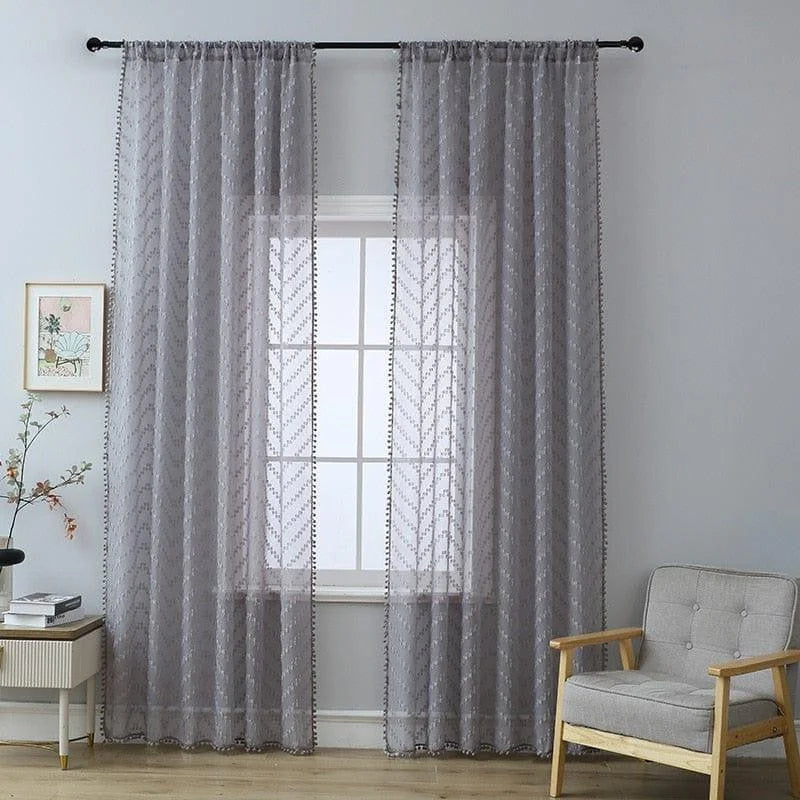 Rideaux transparents gris ornant une fenêtre dans un salon moderne. Ces rideaux à motifs subtils ajoutent une touche élégante et accueillante à la pièce. Idéal pour filtrer la lumière tout en préservant l'intimité, parfait pour un décor intérieur contemporain.