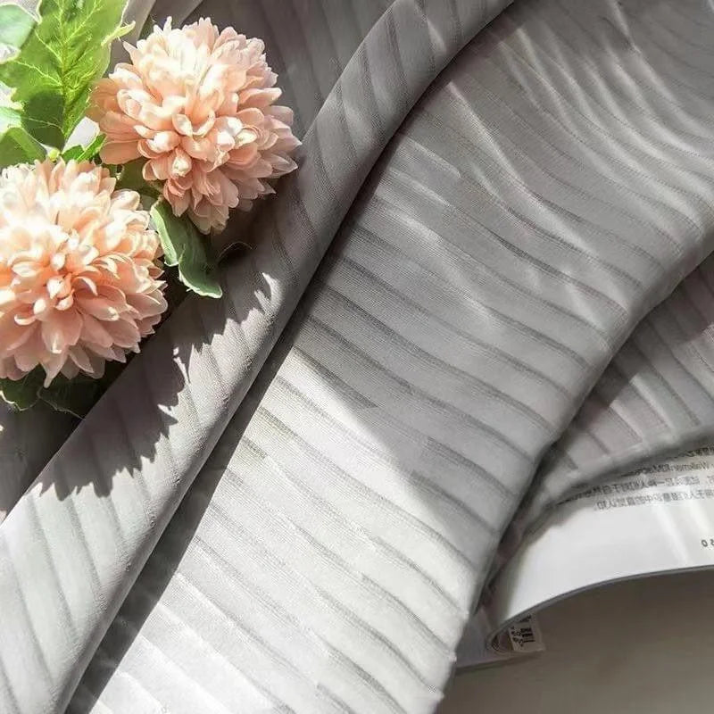 Voilage élégant aux motifs rayés gris clairs, accompagné de fleurs décoratives roses pastel, parfait pour embellir votre intérieur avec une touche moderne et sophistiquée. Idéal pour des ambiances lumineuses et naturelles.