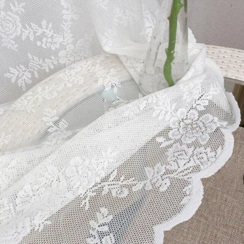 Rideau blanc avec motif floral en transparence sur une table en extérieur, créant une atmosphère élégante et lumineuse. Accessoire de décoration idéal pour ajouter une touche de sophistication à votre intérieur. Parfait pour les salons ou chambres, ce rideau combine esthétique et fonctionnalité.