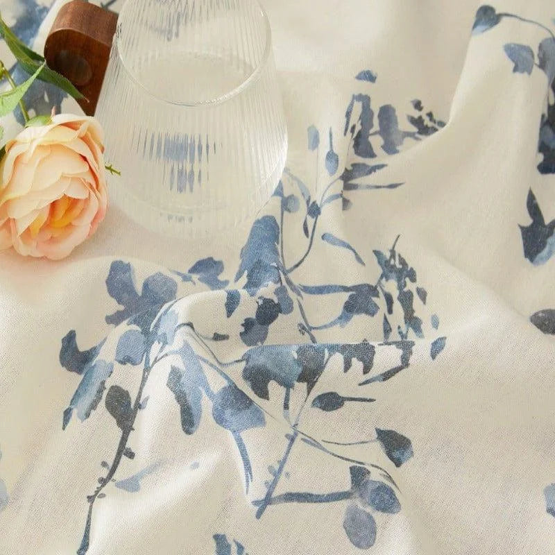 Tenture décorative avec motifs floraux bleus sur fond blanc, accompagnée d'une rose orange et d'un verre élégant. Parfaite pour embellir un intérieur avec une touche naturelle et raffinée. Idéale pour apporter une ambiance paisible et florale à votre salon ou chambre.