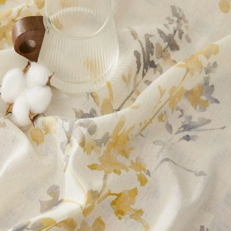 Image d'un tissu élégant aux motifs floraux jaunes et gris, accompagné d'un verre moderne avec anse en bois, offrant une ambiance naturelle et délicate parfaite pour décorer votre intérieur avec style et subtilité.