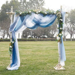 Arche de mariage élégante avec drapés bleu et blanc, idéale pour des cérémonies en plein air. Décorée de fleurs et feuillages, cette arche apporte une touche romantique et naturelle à votre événement. Parfaite pour créer un cadre enchanteur pour des photos de mariage inoubliables.