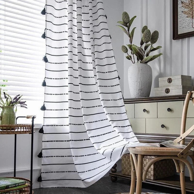 Rideau décoratif blanc à motifs noirs disposé dans un salon lumineux avec un meuble en bois et des plantes vertes, créant une ambiance élégante et moderne. Parfait pour apporter une touche de style épuré à votre intérieur.