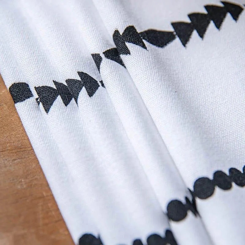 Gros plan sur un tissu blanc avec un motif de flèches noires en zigzag, idéal pour embellir un espace intérieur avec une touche moderne et élégante. Parfait pour créer une ambiance contemporaine et tendance dans votre maison.