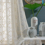 Voilage élégant avec motif géométrique doré, créant une ambiance lumineuse et raffinée. Parfait pour sublimer votre intérieur, ce rideau s'accorde harmonieusement avec des vases décoratifs en porcelaine ornée de motifs floraux. Idéal pour un salon ou une chambre au style classique et sophistiqué.