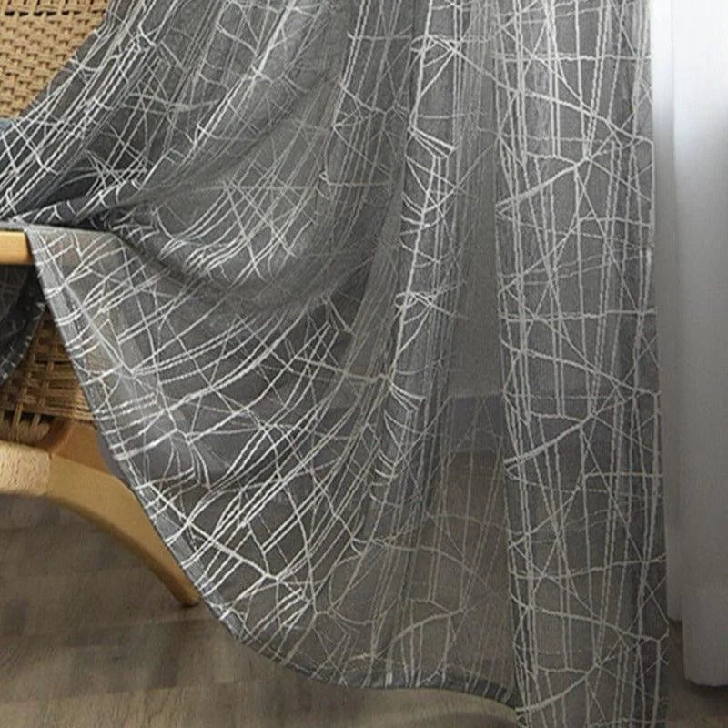 Voilage gris élégant avec motif géométrique blanc, idéal pour ajouter une touche moderne et raffinée à votre décoration intérieure. Parfait pour le salon, la chambre ou le bureau, ce rideau laisse filtrer la lumière tout en garantissant une certaine intimité. Accessoire déco tendance pour habiller vos fenêtres avec style.