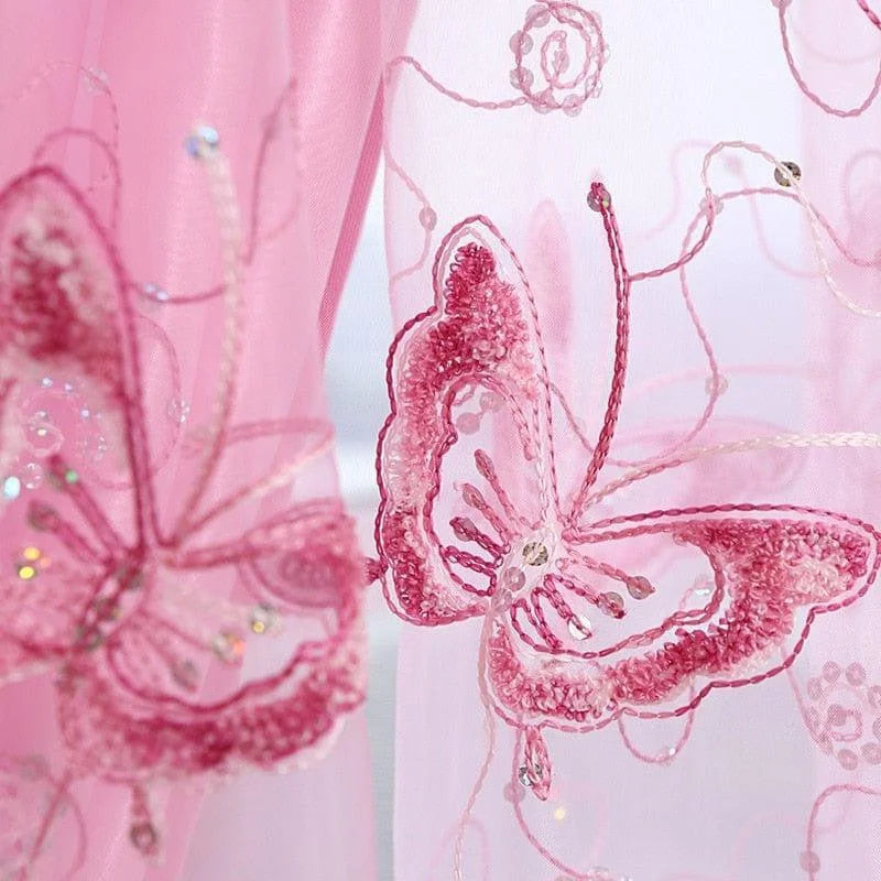 Détail d'un motif floral brodé rose avec des papillons élégants et des accents scintillants, idéal pour ajouter une touche de délicatesse et de sophistication à votre tenue ou décoration intérieure. Design féminin et raffiné, parfait pour des occasions spéciales ou pour embellir votre espace de vie.