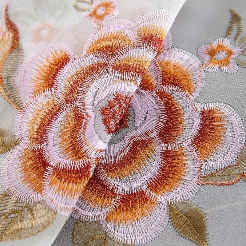 Motif floral brodé élégant sur tissu décoratif, mettant en valeur des nuances de rose et d’orange. Ce design raffiné ajoute une touche artistique et sophistiquée aux vêtements ou à la décoration intérieure. Idéal pour créer une atmosphère chaleureuse et accueillante, parfaite pour embellir tout espace de vie.