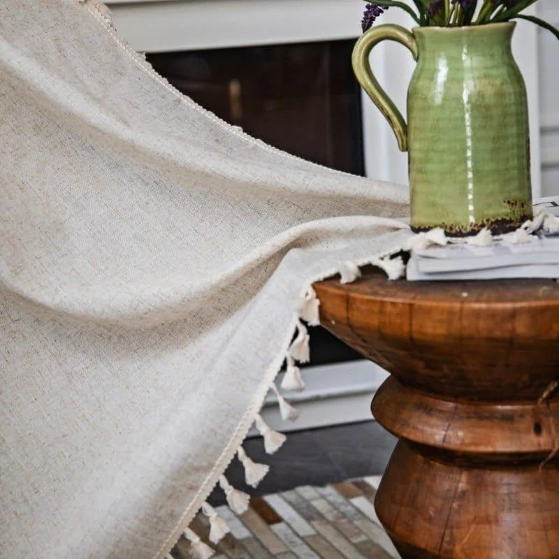 Plaid beige élégant avec franges décoratives, idéal pour ajouter une touche chaleureuse à votre intérieur. Parfait pour le salon ou la chambre, ce plaid apporte une ambiance cocooning et s'harmonise avec divers styles de décoration. Accompagné d'un joli vase en céramique verte sur une table en bois, tout est réuni pour un coin détente accueillant.