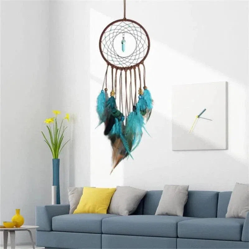 Capteur de rêves suspendu au-dessus d'un canapé bleu moderne, décoré de plumes turquoises élégantes. Parfait pour ajouter une touche bohème à un salon contemporain. Design apaisant et ambiance relaxante assurés avec ce capteur de rêves artistique. Idéal pour la décoration intérieure, en complément avec un élégant vase de fleurs jaunes.