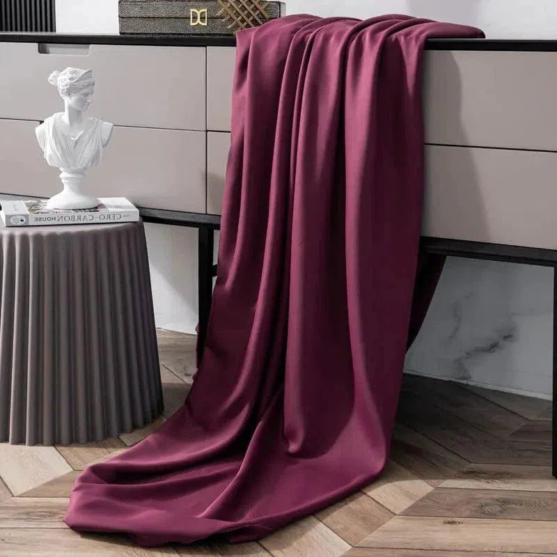 Drapé élégant de couleur bordeaux posé sur un meuble moderne, ajoutant une touche de sophistication à la décoration intérieure. Le sol en bois et le mobilier contemporain créent un espace harmonieux et chaleureux, idéal pour sublimer tout type d'intérieur.