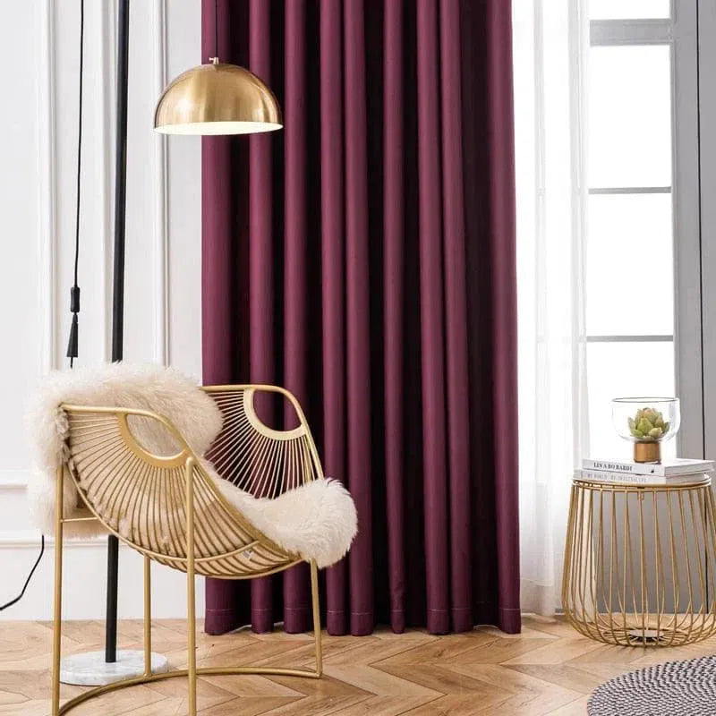 Fauteuil design doré avec coussin moelleux dans un salon moderne, éclairé par une lampe suspendue. Rideau prune et table d'appoint avec plante d'intérieur. Idée déco élégante pour un intérieur chic et chaleureux.