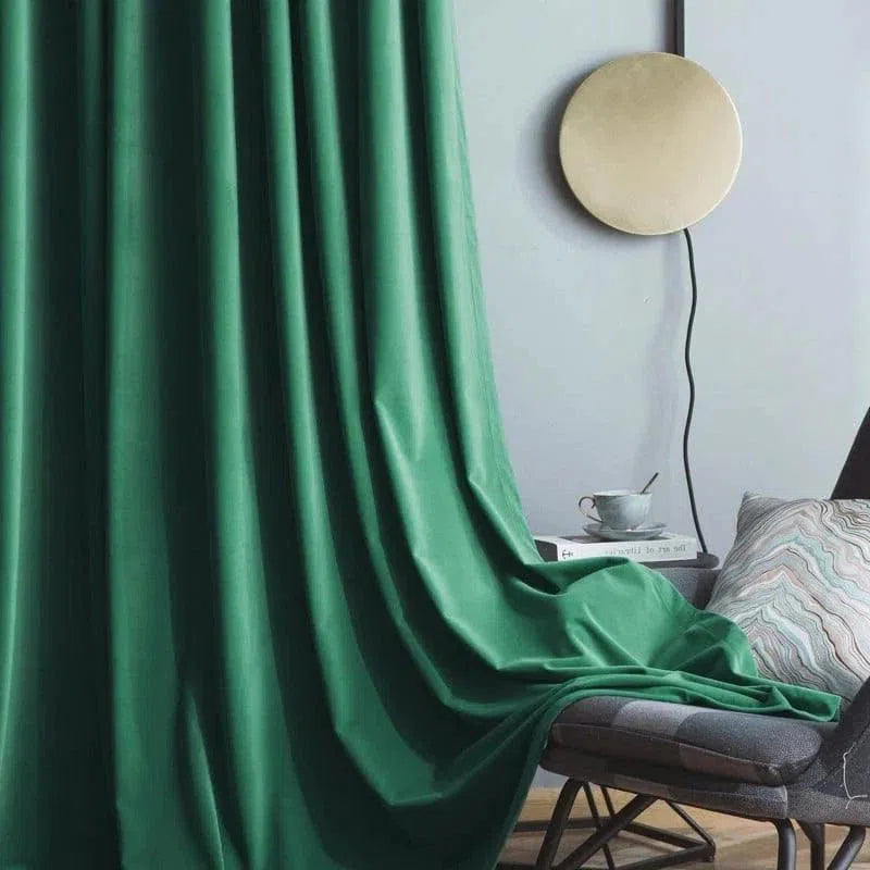 Rideau élégant vert dans un salon moderne avec fauteuil confortable, tasse à café et lampe murale décorative. Parfait pour ajouter une touche de couleur et de sophistication à votre intérieur. Idéal pour le salon ou la chambre, créant une ambiance apaisante et chaleureuse.