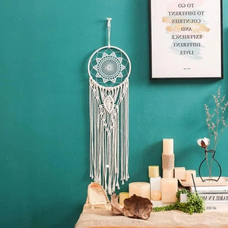 Attrape-rêves mural élégant suspendu devant un mur turquoise dans une ambiance intérieure chaleureuse. Parfait pour ajouter une touche de décoration bohème à votre maison. Idéal pour le salon, la chambre ou un espace zen. Accompagnez-le de bougies et de petits objets déco pour un effet apaisant et harmonieux.
