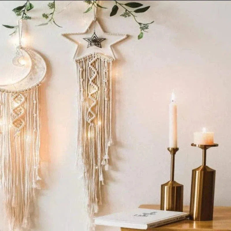 Décoration murale bohème avec tenture en forme de lune et étoile, illustrant un style minimaliste et élégant. Ce design unique apporte une touche chaleureuse et lumineuse à votre intérieur, idéal pour sublimer votre espace avec une ambiance apaisante. Parfait pour le salon, la chambre ou tout espace nécessitant une décoration raffinée. Ces éléments se marient harmonieusement avec des accessoires modernes, comme les chandeliers dorés visibles sur la table en bois, créant
