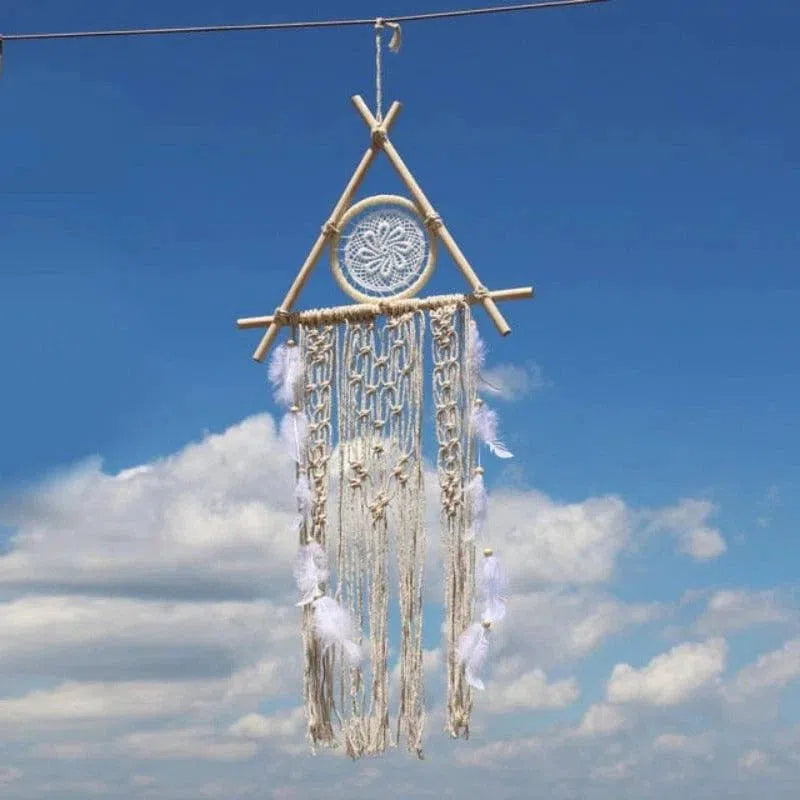 Décoration murale bohème suspendue, composée d'un cercle central avec des plumes blanches et des ornements festonnés, se détachant sur un ciel bleu. Idéale pour une ambiance relaxante et artisanale.