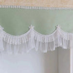 Cantonnière élégante avec détails floraux et plissés blancs, idéale pour apporter une touche de raffinement à n'importe quelle pièce. Cette finition délicate s'intègre parfaitement dans une décoration intérieure romantique et lumineuse, offrant un charme intemporel et élégant à vos fenêtres.