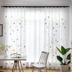 Rideau transparent à motifs géométriques dans un salon moderne, offrant une ambiance lumineuse et élégante. Ce rideau égaye l'espace tout en permettant une diffusion douce de la lumière naturelle. Parfait pour ajouter une touche décorative attrayante à votre intérieur.