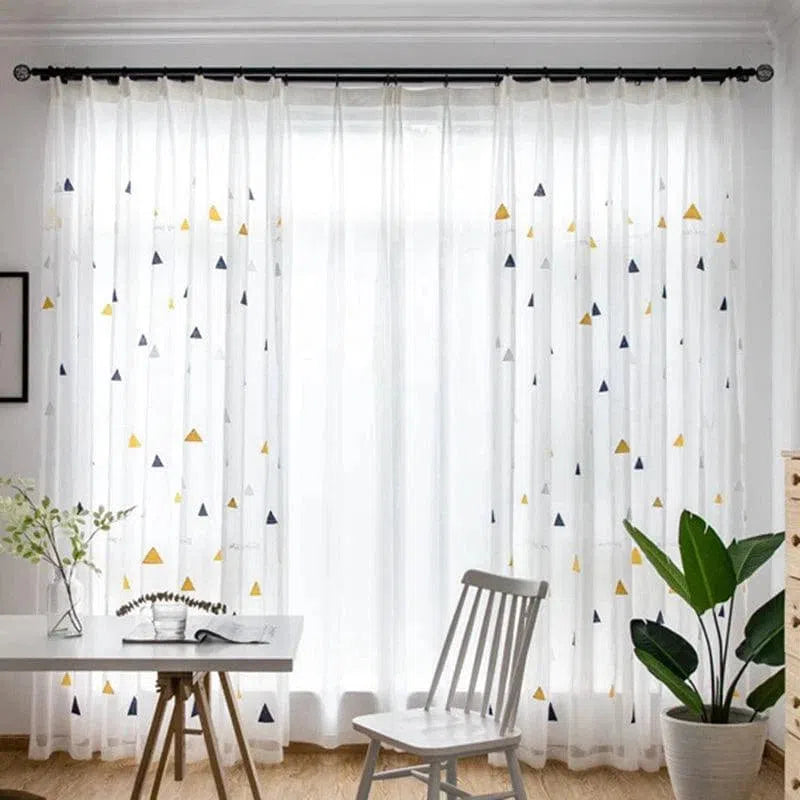 Rideau transparent à motifs géométriques dans un salon moderne, offrant une ambiance lumineuse et élégante. Ce rideau égaye l'espace tout en permettant une diffusion douce de la lumière naturelle. Parfait pour ajouter une touche décorative attrayante à votre intérieur.