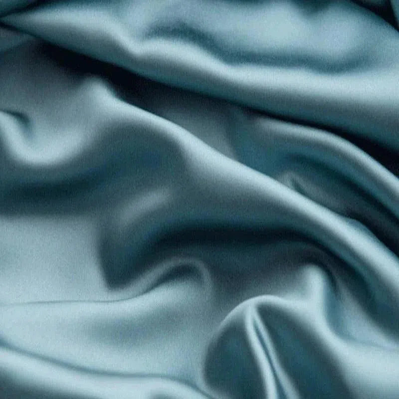 Tissu bleu élégant avec reflets lumineux, offrant une texture soyeuse et ondulée, idéal pour la confection de vêtements de luxe ou de linge de maison raffiné.