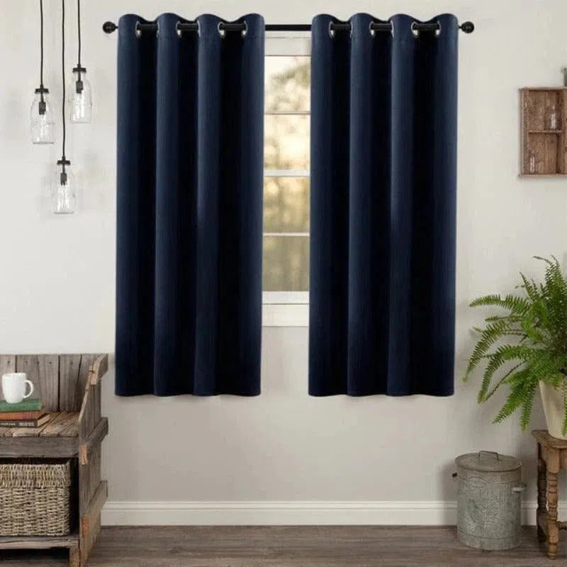 Rideau occultant bleu marine moderne dans une pièce lumineuse, suspendu à une tringle noire. Idéal pour bloquer la lumière et ajouter une touche élégante à votre décoration intérieure. Parfait pour les salons ou chambres à coucher.