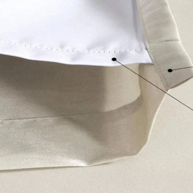 Gros plan sur un rideau d'intérieur blanc et beige, mettant en évidence les détails de couture et les finitions soignées, parfait pour ajouter une touche moderne et élégante à votre salon ou chambre.