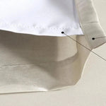 Gros plan sur un rideau d'intérieur blanc et beige, mettant en évidence les détails de couture et les finitions soignées, parfait pour ajouter une touche moderne et élégante à votre salon ou chambre.