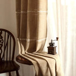 Rideau élégant de couleur beige avec motifs brodés subtils, idéal pour ajouter une touche chaleureuse et accueillante à votre intérieur. Accessoire de décoration parfait pour le salon, la chambre ou la salle à manger, offrant une ambiance cosy. Accessoire complémentaire à côté d'une chaise en bois classique et d'un moulin à café vintage.