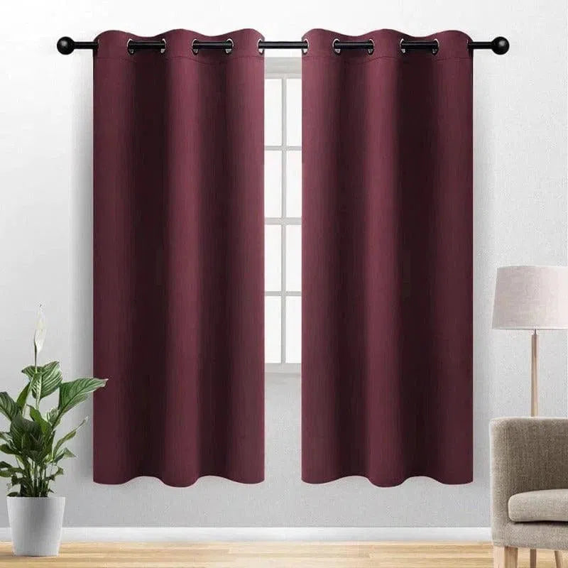 Paire de rideaux occultants à œillets, couleur aubergine, suspendus devant une fenêtre dans un salon moderne. Parfaits pour bloquer la lumière et offrir une intimité optimale. Accessoire élégant pour embellir votre intérieur.