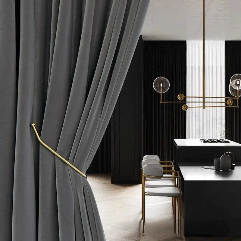 Rideau élégant gris foncé dans un intérieur moderne, avec un embrasse en métal doré, ajoutant une touche de sophistication au salon, combiné avec un mobilier chic et contemporain sous un éclairage design.