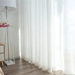 Rideau en voile blanc moderne dans un salon lumineux, offrant une ambiance élégante et épurée. Ce rideau léger et transparent permet de filtrer délicatement la lumière naturelle, tout en préservant l'intimité de votre espace. Idéal pour une décoration intérieure contemporaine.
