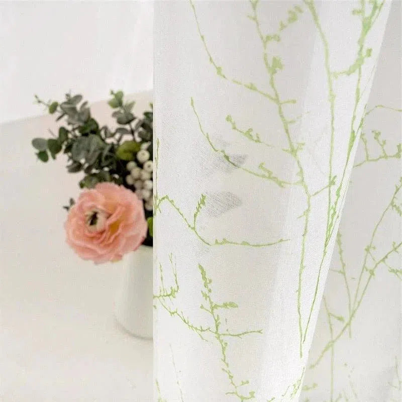 Rideau décoratif avec motif végétal vert, parfait pour une ambiance naturelle et élégante dans votre intérieur. Idéal pour apporter une touche de fraîcheur et de modernité à vos espaces. Accessoire d'intérieur stylé avec fleurs en arrière-plan.
