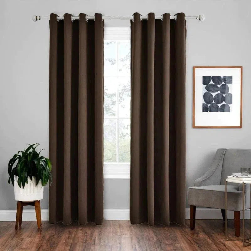 Rideau élégant marron suspendu sur une tringle, apportant une touche moderne à un salon. Le rideau encadre parfaitement une grande fenêtre, offrant intimité et style. À côté, un fauteuil gris et une plante verte en pot ajoutent une ambiance chaleureuse. Idéal pour tout intérieur contemporain.