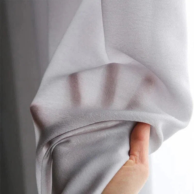 Voilage élégant blanc translucide laissant passer la lumière, parfait pour créer une ambiance lumineuse et chic dans n'importe quelle pièce. Ce rideau de qualité supérieure offre à la fois intimité et style raffiné. Idéal pour les salons modernes ou les chambres chaleureuses.