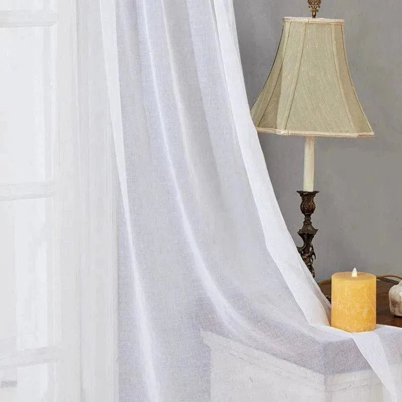 Voilage blanc élégant pour fenêtre, offrant une atmosphère lumineuse et apaisante à votre intérieur. Idéal pour illuminer le salon ou la chambre tout en préservant l'intimité. Accessoire décoratif parfait pour compléter un décor classique avec une touche de chaleur grâce aux éléments de la pièce, comme la lampe vintage et la bougie décorative.