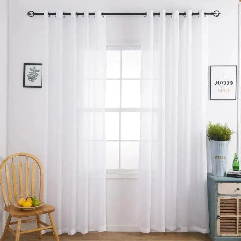 Rideaux transparents élégants et classiques encadrant une fenêtre lumineuse, parfaits pour ajouter une touche moderne à n'importe quelle pièce. Décoration simple avec une chaise en bois et des cadres muraux délicats, créant une ambiance paisible et accueillante.