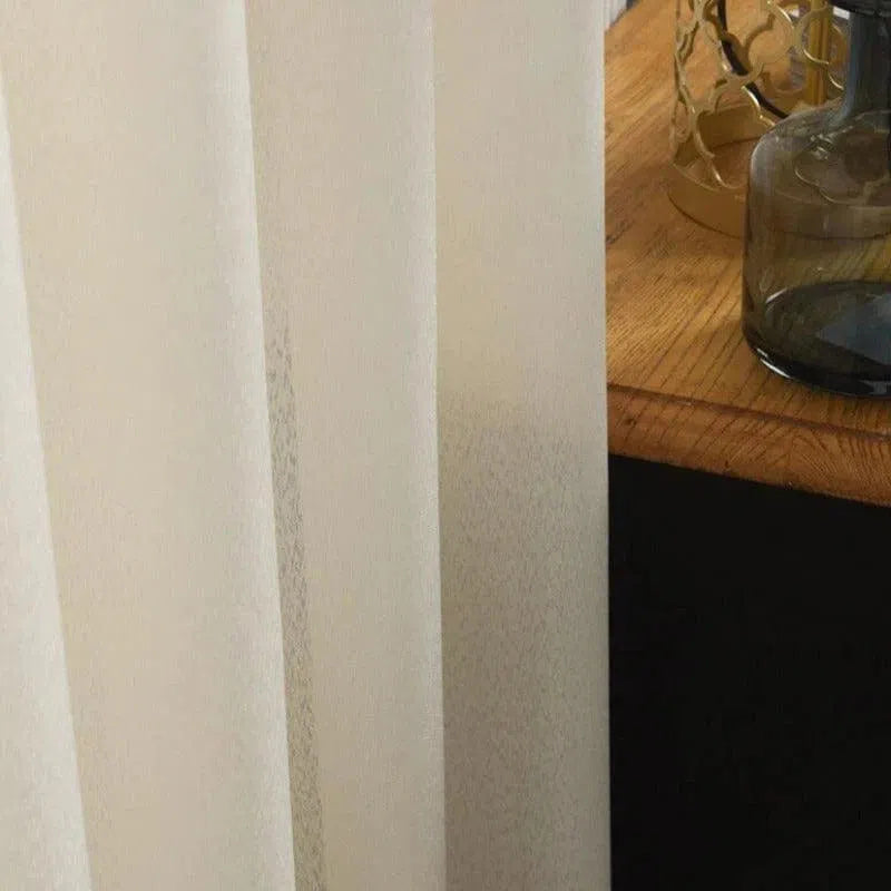 Rideau beige élégant suspendu dans un intérieur moderne avec une table en bois ornée de décorations. Idéal pour apporter une touche de sophistication et d'intimité à votre espace de vie.