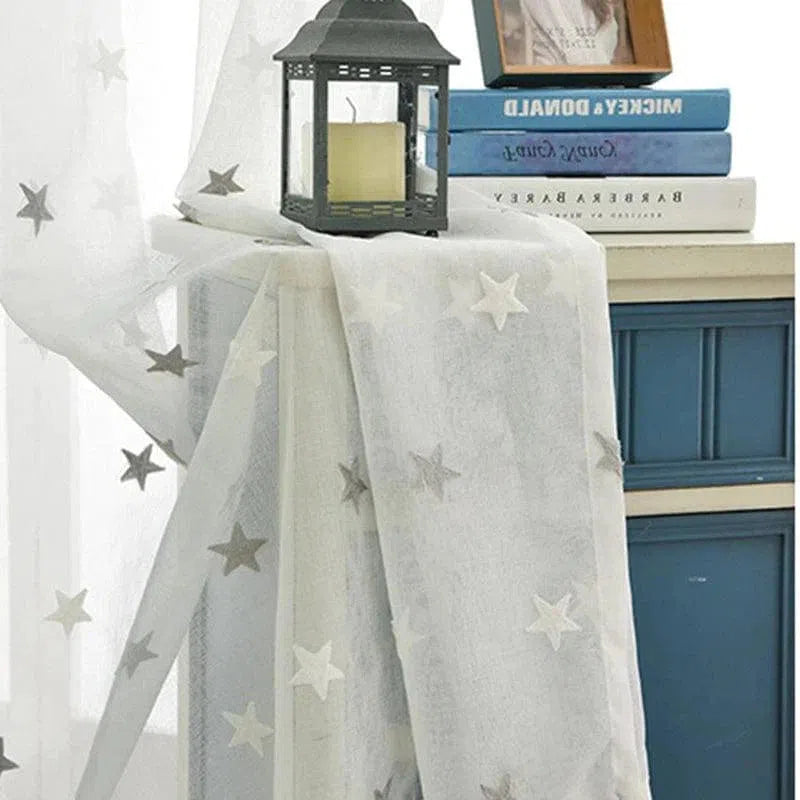 Voilage décoratif blanc avec motifs étoiles grises, idéal pour chambre d'enfant ou salon moderne. Ce rideau transparent apporte une touche élégante et féérique à votre intérieur. Combine design doux et ambiance lumineuse pour sublimer votre espace de vie. Parfait pour créer une atmosphère apaisante et accueillante.