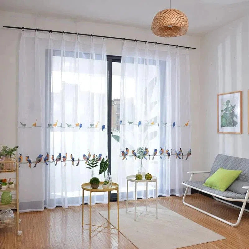 Rideau transparent blanc avec motifs d'oiseaux colorés, idéal pour ajouter une touche de nature et d'élégance à votre salon. Crée une ambiance lumineuse et aérée, parfait pour les espaces de vie modernes et accueillants. Accessoire décoratif tendance pour habiller une grande fenêtre ou une baie vitrée.