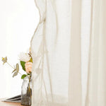 Voilage élégant beige pour salon moderne, laissant filtrer une douce lumière naturelle, avec vase décoratif et fleurs délicates en arrière-plan. Optimisé pour un intérieur chaleureux et accueillant.