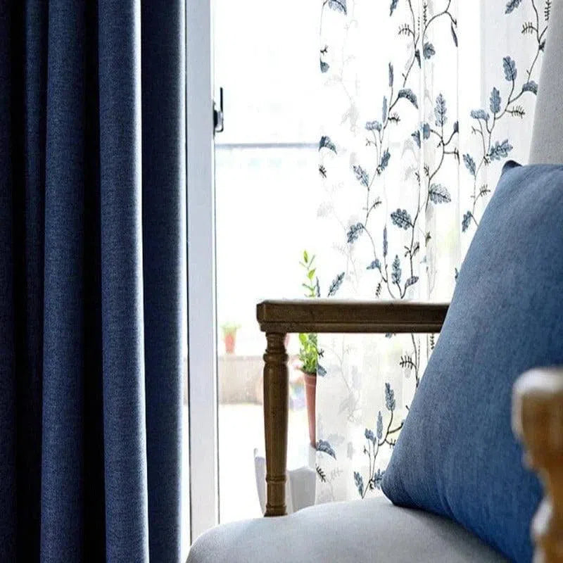 Rideau de salon bleu foncé avec motifs floraux, complété par un fauteuil élégant et confortable, idéal pour une décoration intérieure moderne et chaleureuse. Parfait pour filtrer la lumière tout en ajoutant une touche d'élégance à votre pièce.