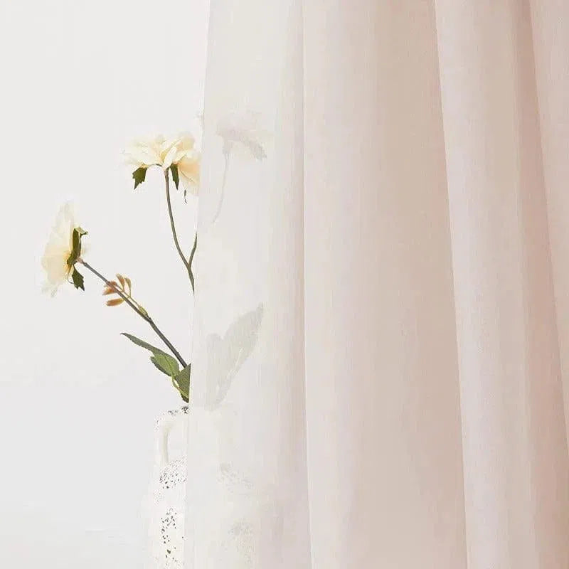 Rideau translucide beige élégant, idéal pour ajouter une touche de sophistication et de douceur à n'importe quelle pièce. Design épuré qui laisse passer la lumière tout en préservant l'intimité. Parfait pour le salon ou la chambre à coucher. Décoration naturelle avec des fleurs en arrière-plan.